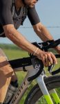 Gravel cyclist racing through the Kansas Flint Hills at Unbound XL, with an Apidura top tube pack mounted to a Scott frame.